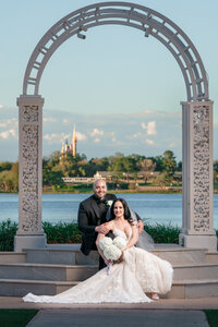 Bride and groom seated by the water near a gazebo at a Disney Orlando wedding