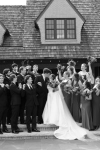 black and white image of bride and groom posing with their wedding party