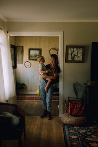 A mother holds her son during an at home family photo session in Houston TX