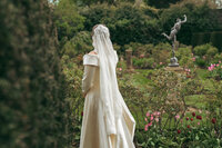 Bride from behind in a garden with a classical statue, Keith Marrison Oxfordshire wedding photographer