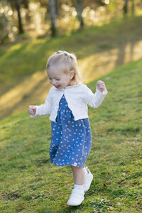 daughter standing on a hill wearing a blue dress with a white cardigan