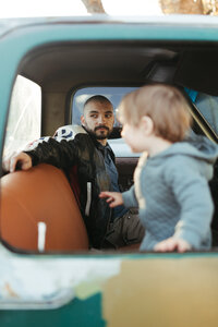 Father sitting in vintage truck with son during an at home photo family photo session in Houston Texas