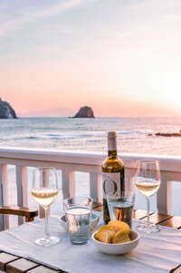 Luxury seaside dining setup with white wine overlooking a Mediterranean sunset