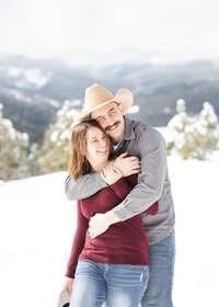 Couple laughing and embracing in the snow at engagement session in Mt. Falcon Trail.