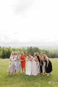 group of friends leaning on bride and together after her wedding in Maine