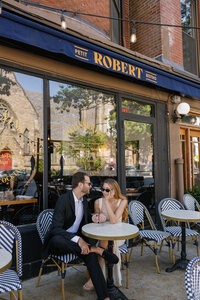 Couple sharing a drink outside the le Robert in Boston during an engagement photo shoot.