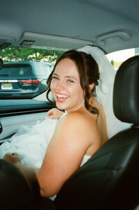bride sitting in in the front seat of the car looking back