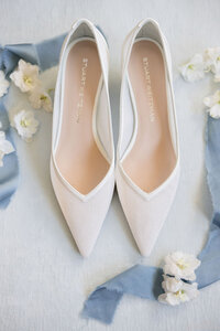 White Stuart Weitzman bridal heels styled with dusty blue ribbon and flowers