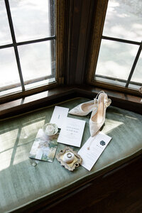 wedding shoes and accessories sitting in shadows on a green window seat