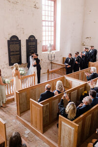 Bride and groom sharing their first kiss during an intimate wedding ceremony inside St Martin's historic chapel.