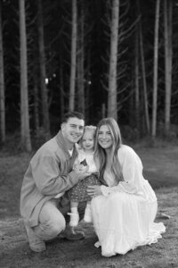 mother and father posing with their child in the forests of ohio