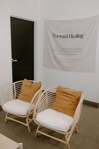 two chairs outside of an office space in front of a forward healing therapy banner