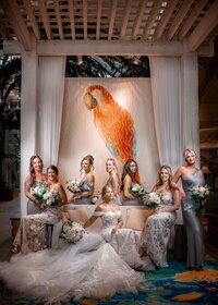 Wedding party posing by a colorful parrot backdrop at an Orlando wedding
