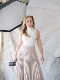Sarah DiCicco laughing while holding her camera in the studio