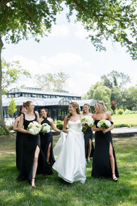 bride wearing white standing with her bridesmaid dressed in black with white bouquets