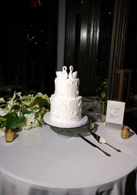 Luxury wedding reception details featuring a textured three-tier wedding cake, romantic floral arrangements, candlelight, and modern reception décor photographed with a documentary storytelling approach.