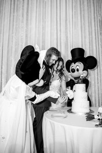 Bride and groom cutting their cake with Mickey Mouse at a Disney World wedding in Orlando