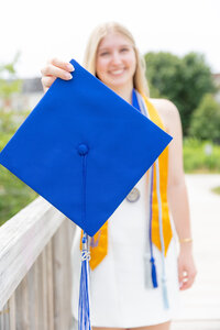 A classic photo taken by Studio Roscher of a happy high school female graduate with a blue graduation cap in Alexandria, VA