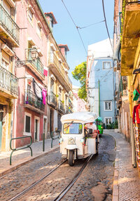 Colorful Mediterranean village street with pastel buildings, balconies, and local shops