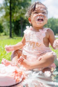 A glossy photograph taken by Studio Roscher of a sad birthday girl with cake in a park in Richmond, VA