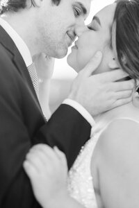 Intimate black-and-white wedding portrait of a bride and groom sharing a kiss.