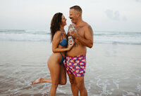 Couple laughing together on the beach during a relaxed portrait session captured by Angie Rich Photography, a San Antonio portrait photographer.