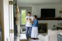 mother and father looking down happily at their baby during in-home newborn session