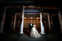 Bride and groom at night in front of an illuminated Disney wedding venue in Orlando