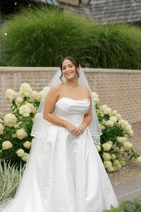 bride smiling at the camera, posing in front of white hydrangeas