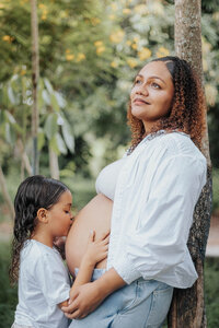 girl kissing pregnant moms belly