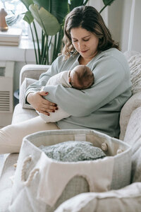 mother holding newborn baby on a couch