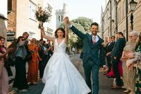 Bride and groom celebrating joyfully with guests outdoors on their wedding day
