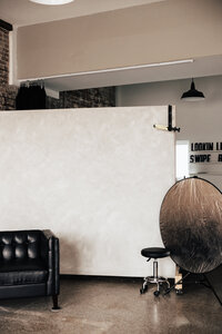 Interior of Love, Kay Collective’s Tampa boudoir studio featuring a leather couch, backdrop wall, and photography gear, modern, minimal space designed for confidence-filled sessions.