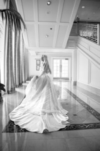 Black and white portrait of a bride in her gown in an elegant venue hallway