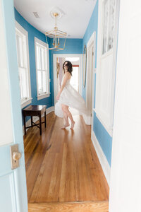 Bride twirling in her wedding dress inside a light-filled coastal home in Delaware before the ceremony.