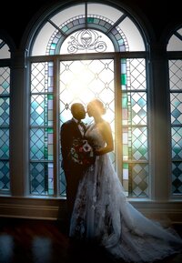 romantic wedding photo of couple against Disney inspired stained glass window