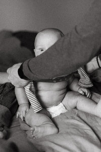 A baby peeks over his fathers arm during an at home newborn session in Houston Texas