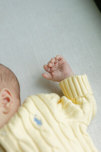 close up of newborn's hands wearing a yellow sweater