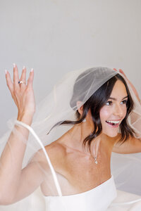 Bride laughs with her veil lifted in a close up bridal portrait