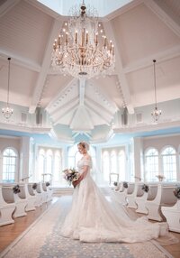 Bride in her gown in a bright ballroom with a chandelier at an Orlando wedding venue