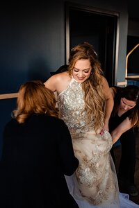Wedding planners with Weddings & Events by Raina assist bride with her shoes and wedding gown