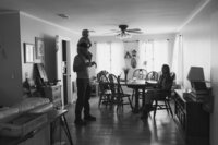 A family sits in their dining room and a father holds his son on his shoulders during their at home family photo session near houston texas