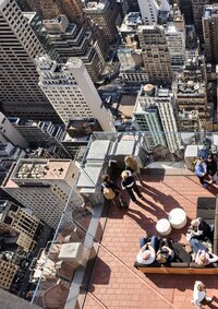 Terracotta-tiled rooftop terrace overlooking the stone and masonry buildings of Midtown Manhattan.