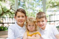 A glossy photograph taken by Studio Roscher of 2 happy kids and 1 grumpy one outside in a park in Savannah, GA