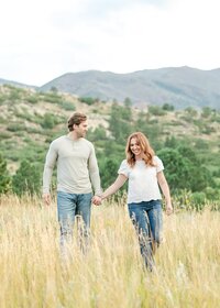 Couple holding hands and walking through mountains in Colorado Springs at Ute Valley Park.