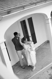 mother and father holding baby while dancing outside for candid photos