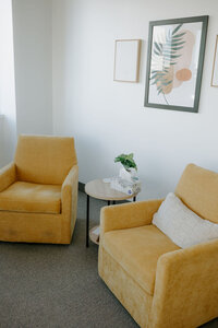 two yellow chairs with end table in between them.