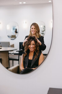 client sitting in a chair looking in the reflection admiring their hair volume and curls