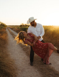 Couple sharing a playful embrace on a Texas country road during sunset engagement photos by Angie Rich Photography in San Antonio.