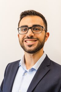 A classic professional portrait taken by Studio Roscher of a male professional smiling in a suit in a studio